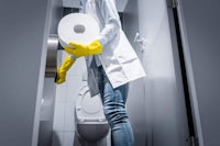 a woman in yellow gloves is holding a roll of toilet paper
